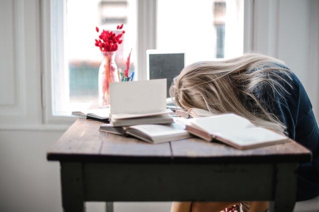 Woman asleep over books at table